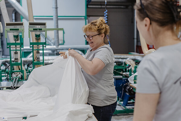 Eine Mitarbeiterin in der Produktion füllt eine Bettdecke.