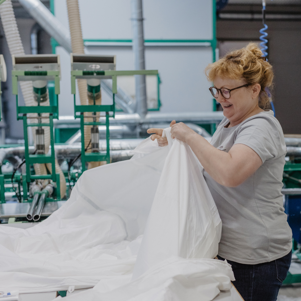 Eine Mitarbeiterin in der Produktion füllt eine Bettdecke.