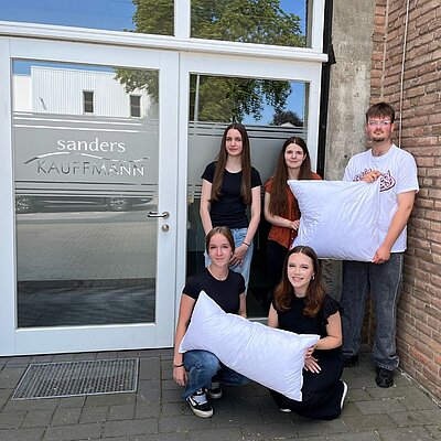 Fünf Auszubildende für ein Gruppenfoto; drei stehen, zwei hocken davor, alle blicken in die Kamera.